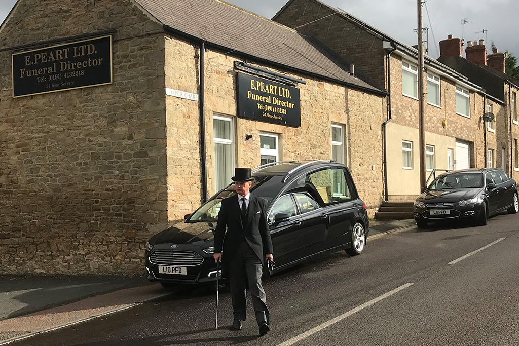 Funeral Director and hearses in from of the E Peart Funeral Director building